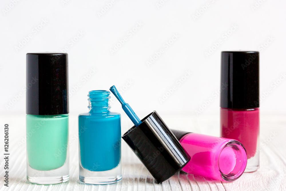 open bottles of nail polish on wooden background close up