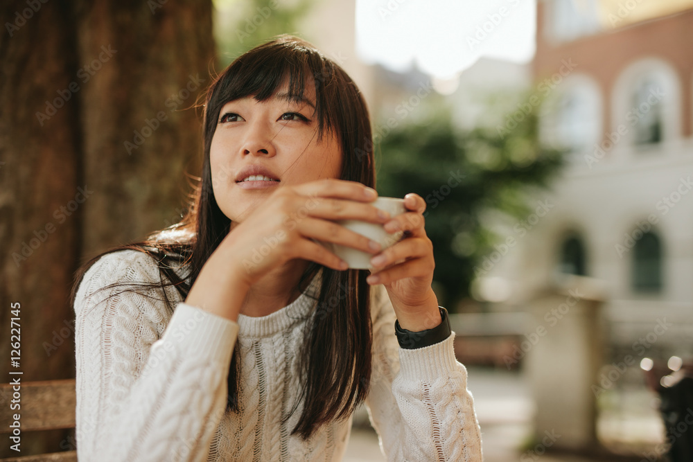 美丽的年轻中国女人在咖啡馆喝咖啡