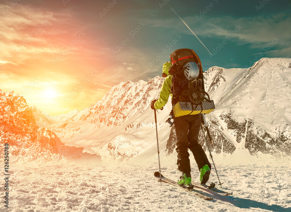 滑雪时背着背包的男人在阳光下登上山顶