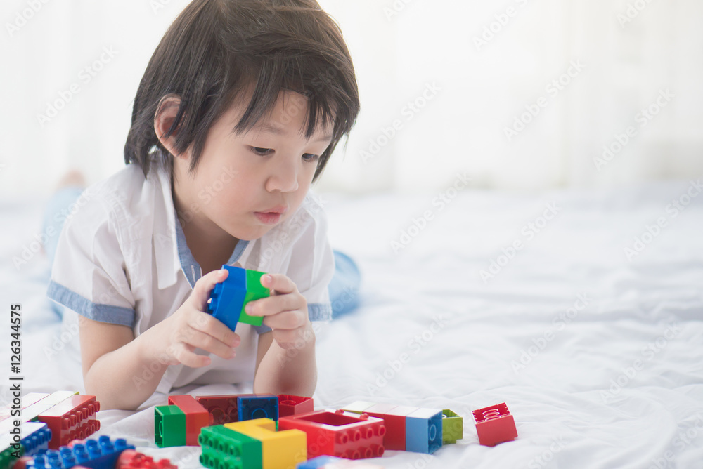 asian child playing with colorful construction blocks