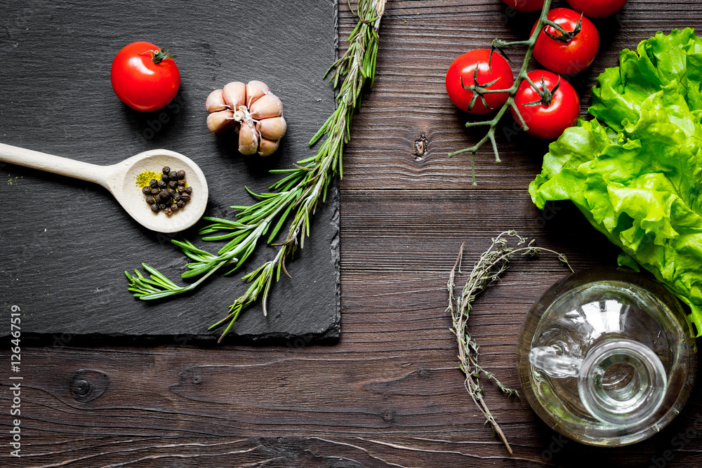 tomato, rosemary and garlic on dark wooden background top view