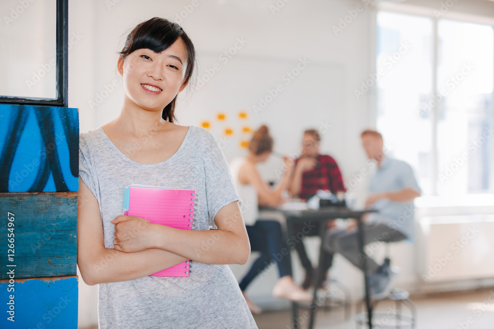 Smiling young asian woman standing in office