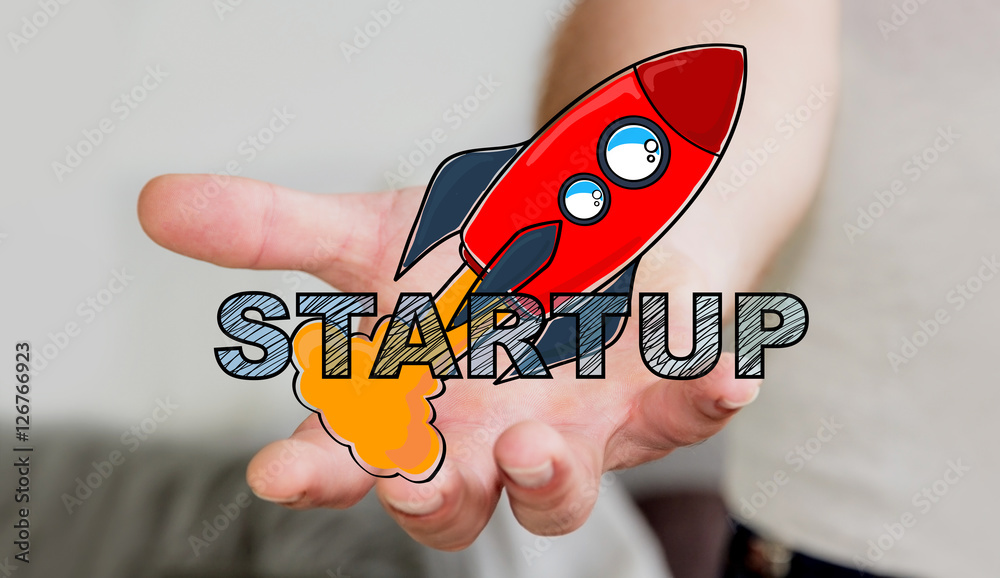 Businessman holding hand drawn startup text and red rocket