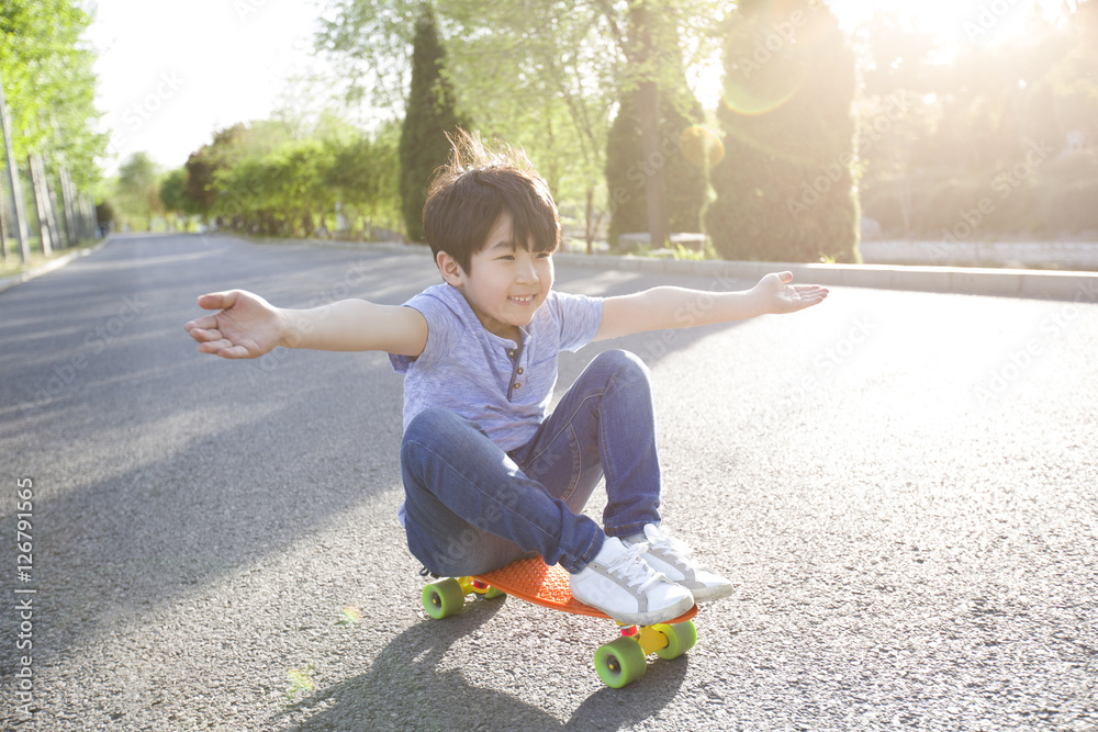 Little boy sitting on a skateboard