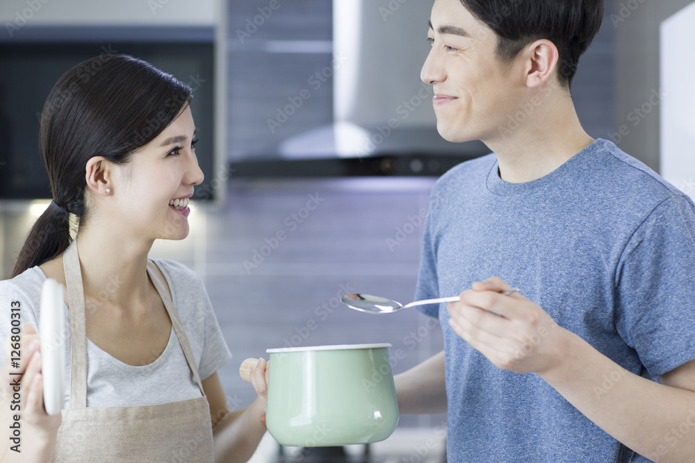 Happy young couple cooking in kitchen