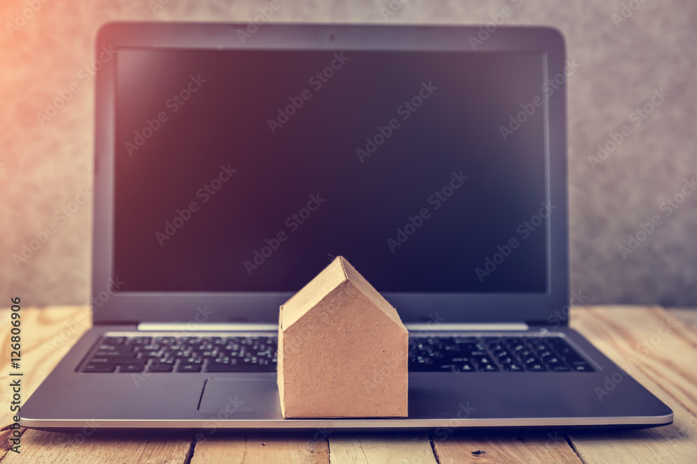 house concept with cardboard model next to black screen notebook