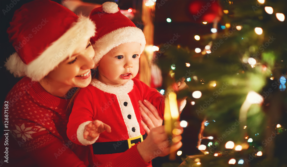 happy family mother and baby near Christmas tree in holiday nigh