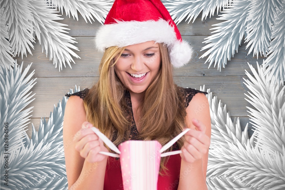 Excited woman in santa hat looking at christmas gift