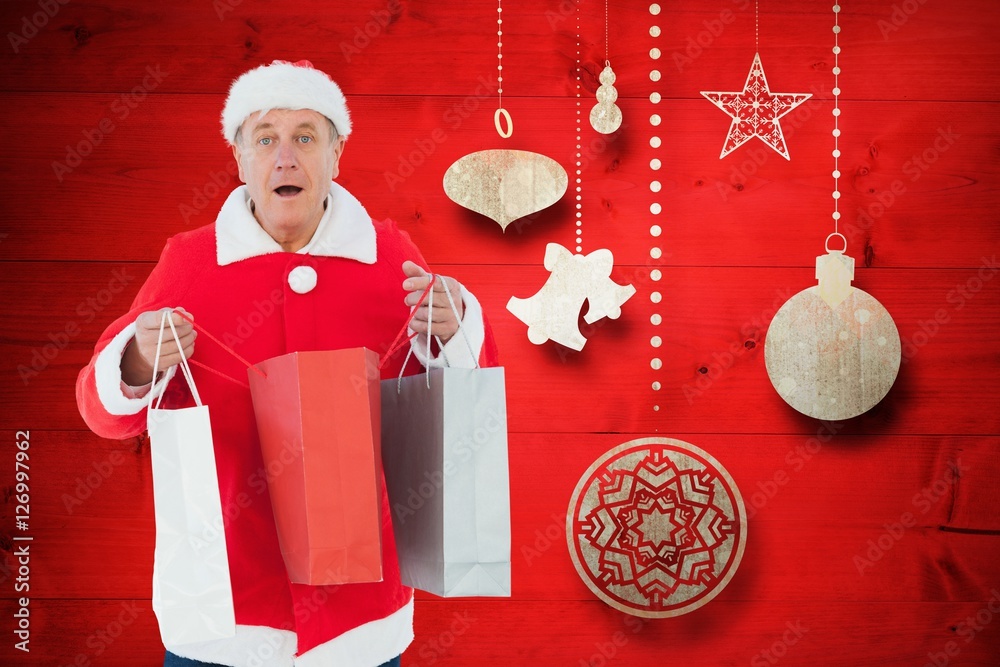 Man in santa costume holding shopping bags against digitally gen