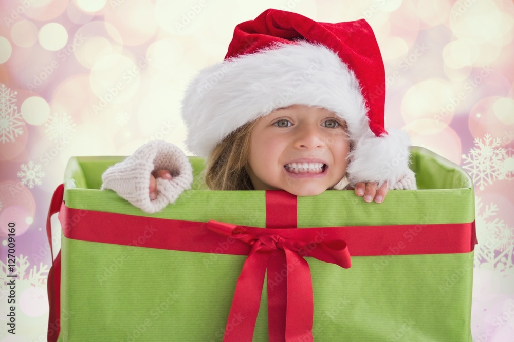 Little girl in santa hat sitting in the gift box