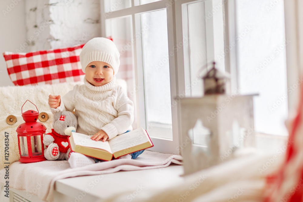 happy baby sitting on window of house in winter