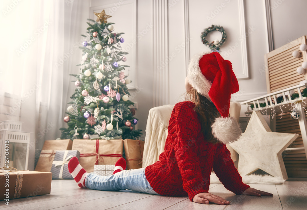 Kid sitting near Christmas tree indoors