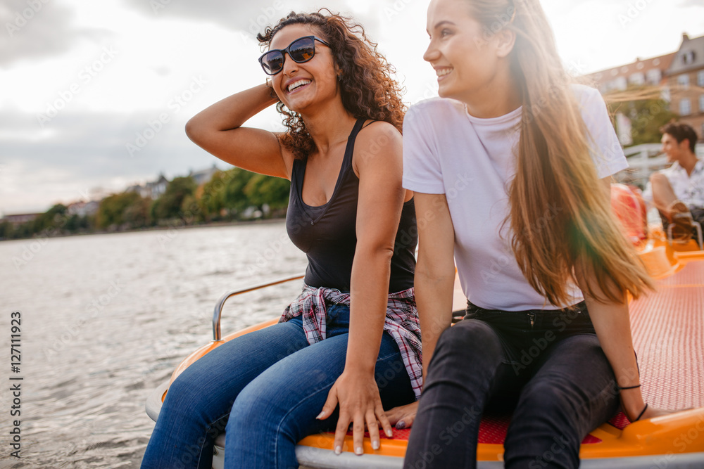 Friends relaxing on pedal boat in lake