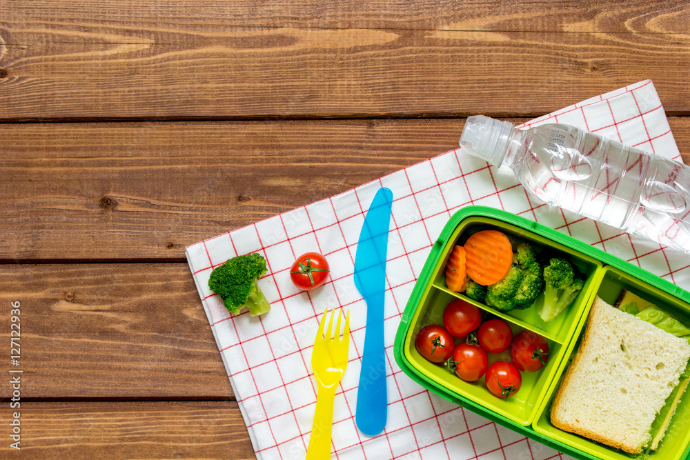 green lunch box for kid on wooden background top view