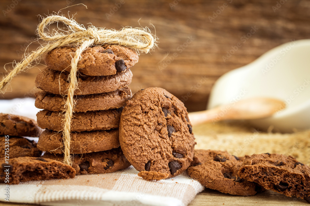 Close up stacked chocolate chip cookies on  napkin with wooden 