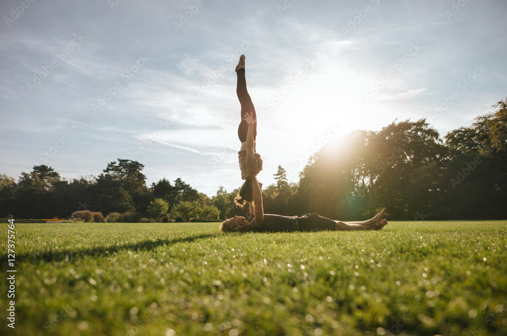 Couple doing pair yoga in park