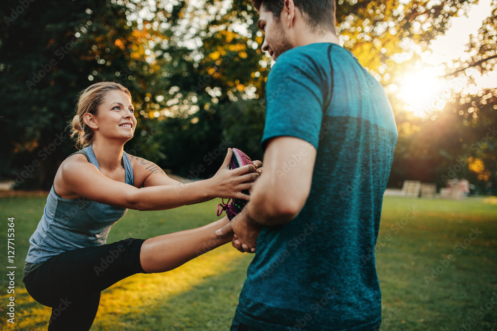 Physical trainer assisting woman with leg exercise