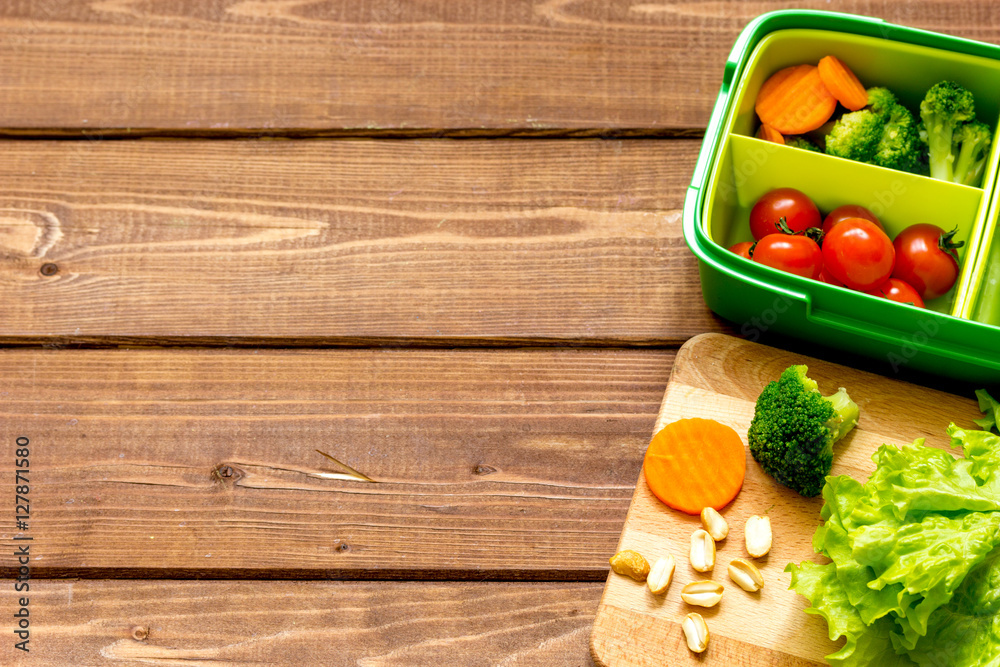 lunch box for kid with fresh vegetables on wooden background