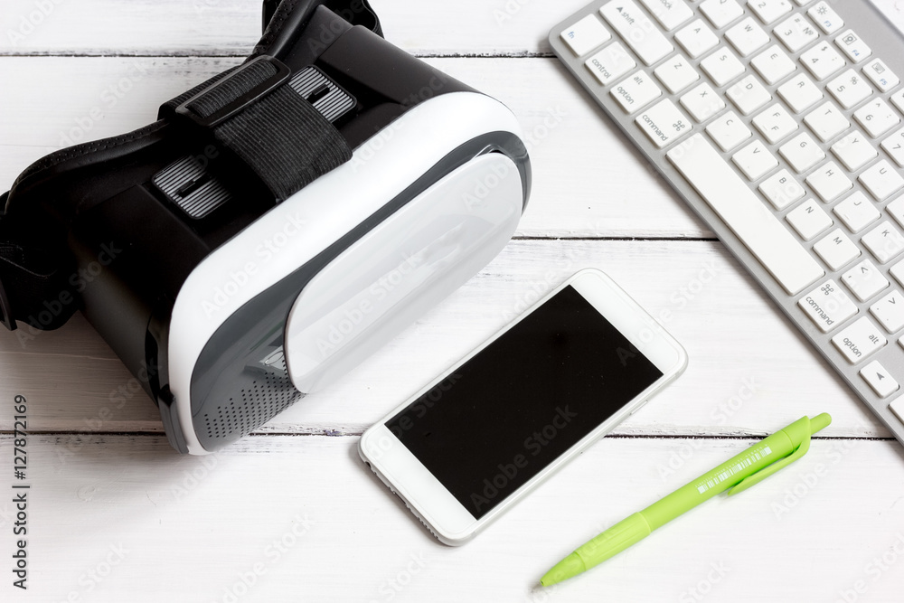 virtual reality glasses with smartphone, keyboard on wooden background