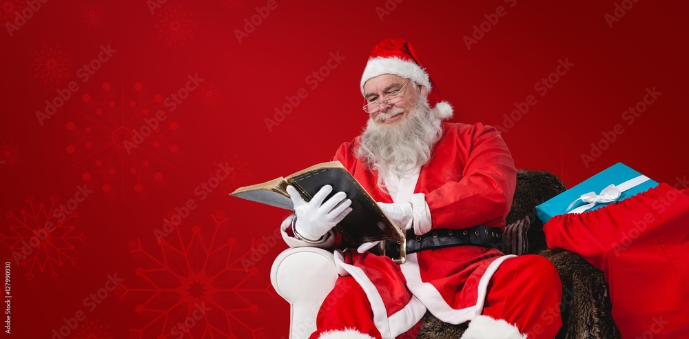 Composite image of santa reading bible with sack of present