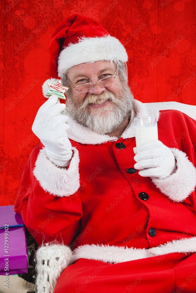 Composite image of santa claus holding glass of milk and star sh