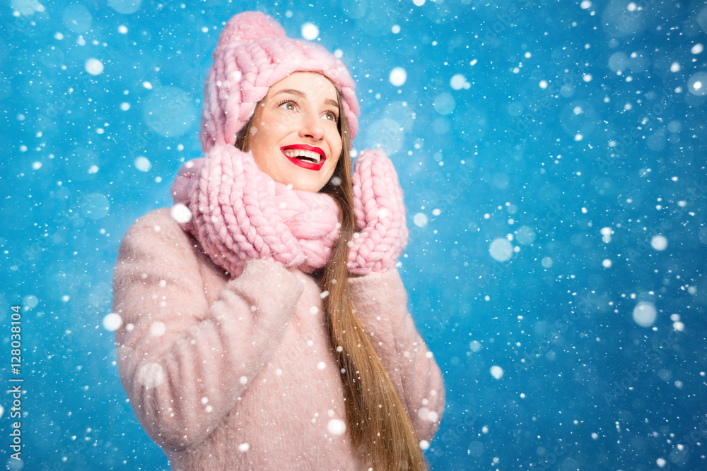 一位穿着针织粉色皮屑、手套和帽子的美女的冬季肖像，帽子上有雪花