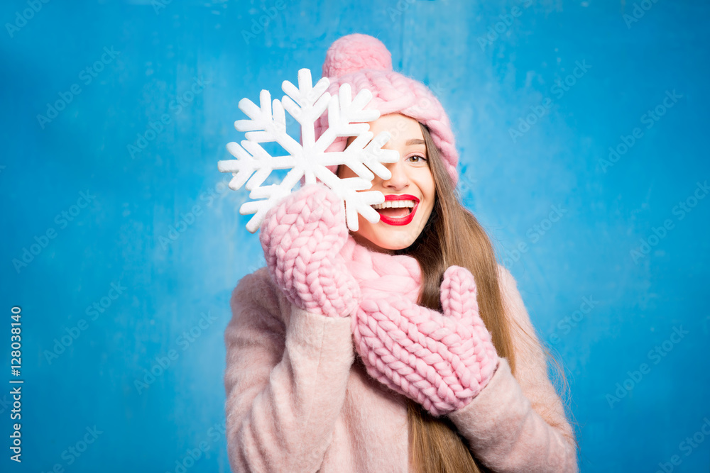 一位穿着针织粉色皮屑、手套和帽子的美女的冬季肖像，帽子上有雪花