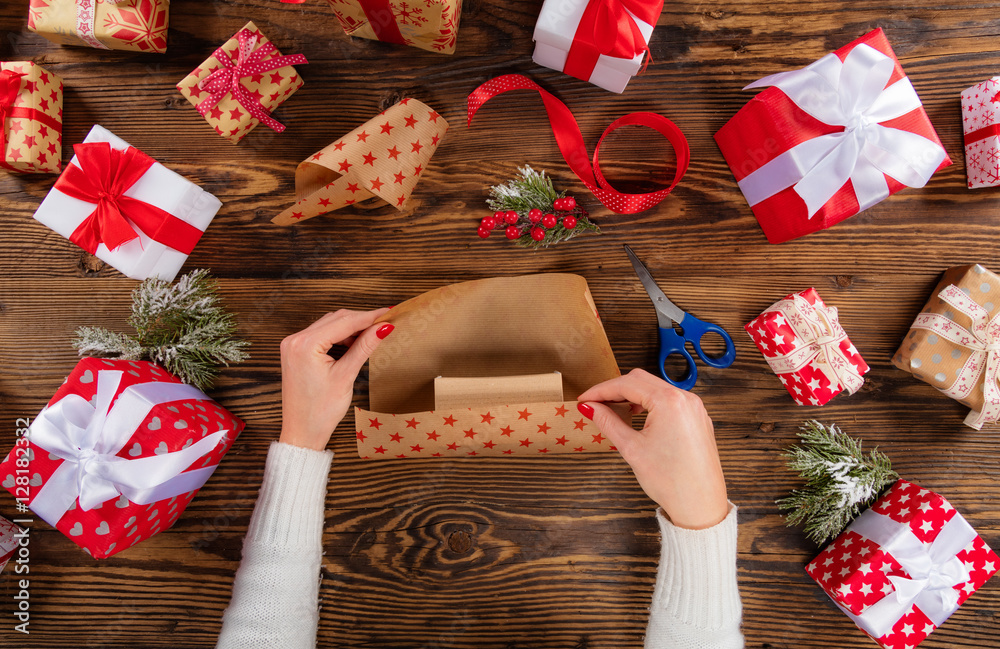 Woman packing Christmas presents on wooden table background