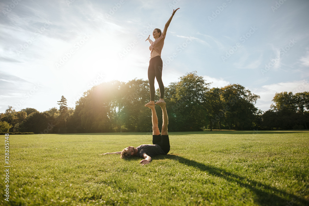 Couple doing acrobatic yoga exercise at park