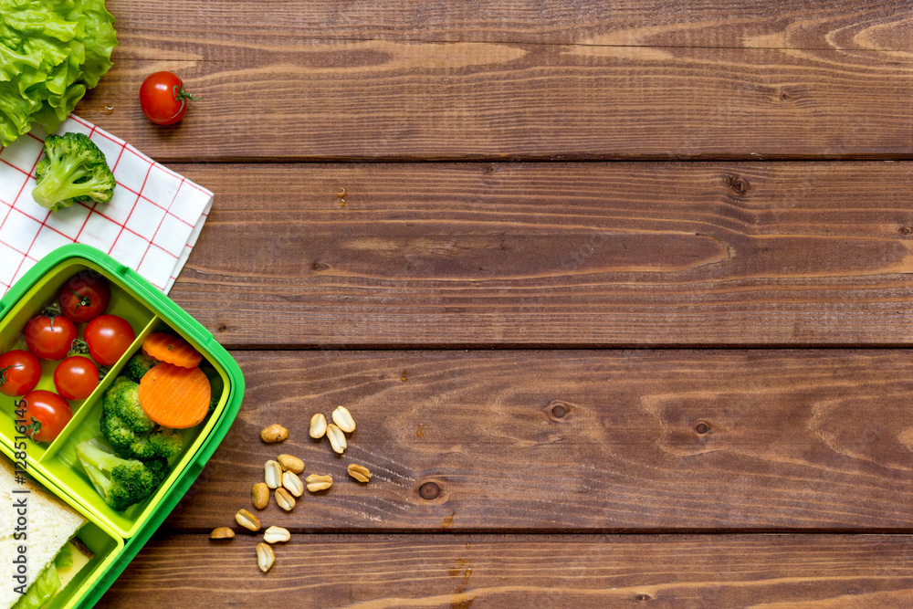 green lunch box for kid on wooden background top view