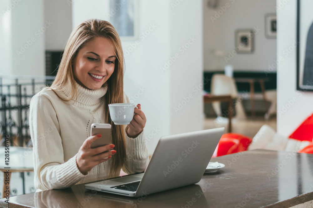 Young business woman drinking coffee and texting on mobile phone