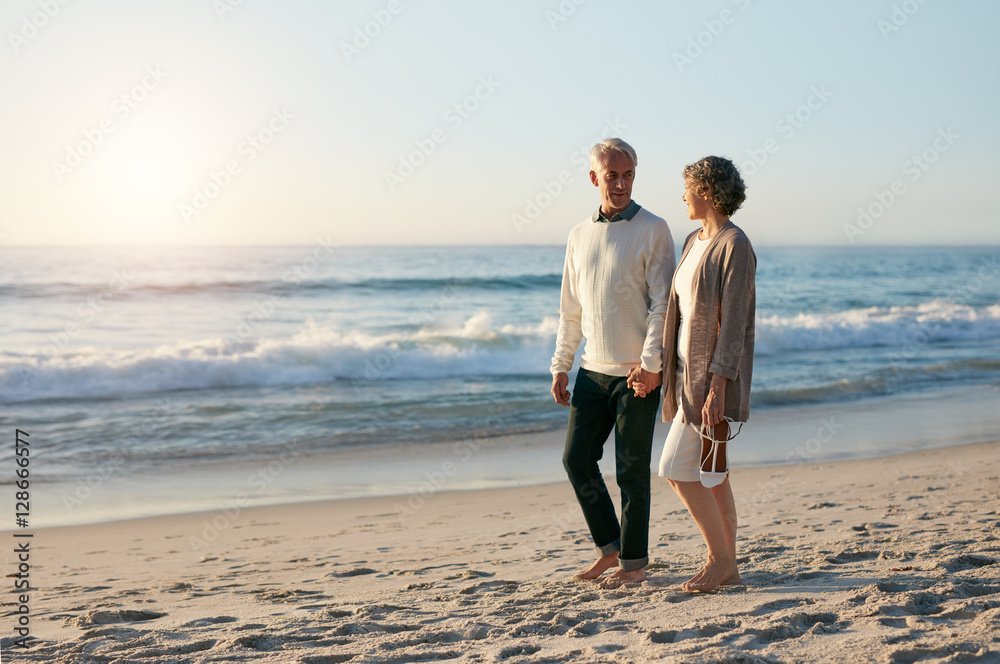 Loving senior couple walking along the beach in evening