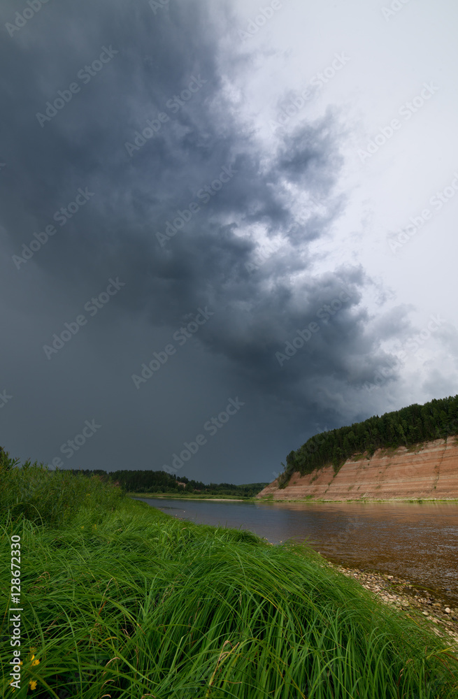  Сurling storm cloud over the river bank. Vertical picture of l