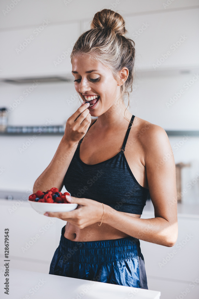 厨房里吃浆果的漂亮年轻女人