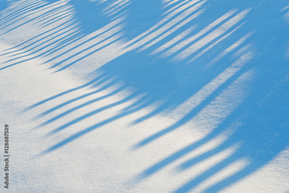 雪堆上围栏上的蓝色阴影。