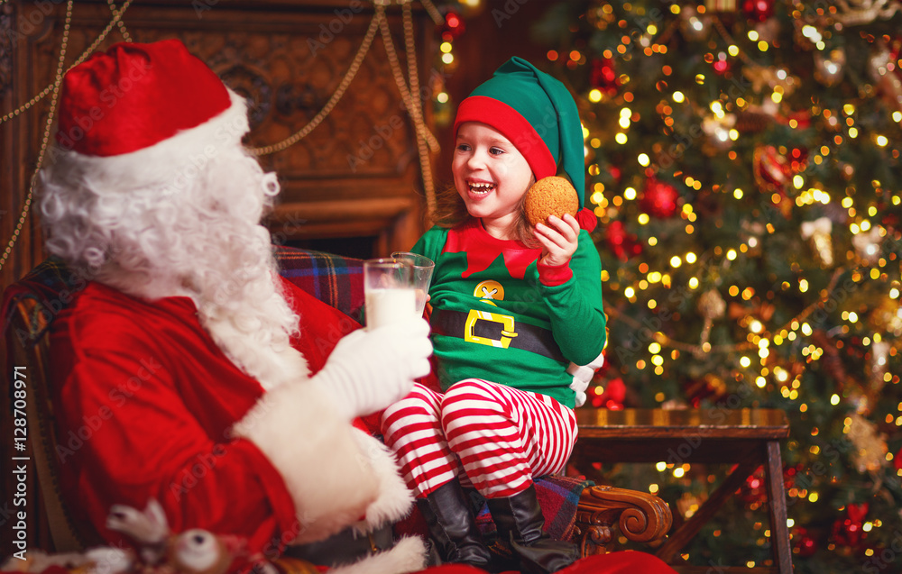 Santa Claus and elf child in Christmas drinking milk and eating