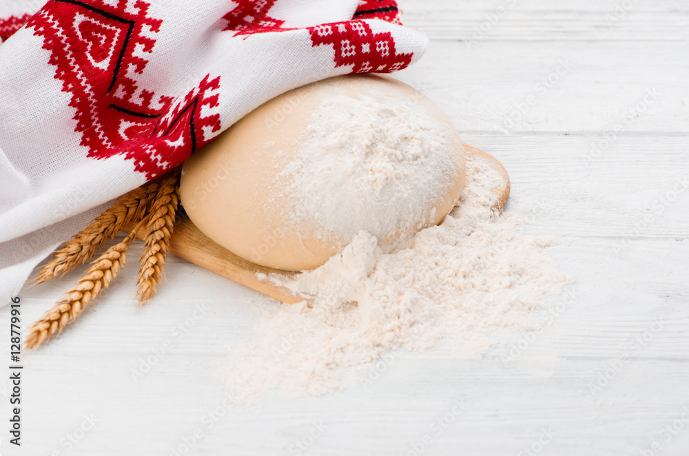 Ball of raw dough isolated on white wooden table with ears wheat and napkin. Copy space. Package. To