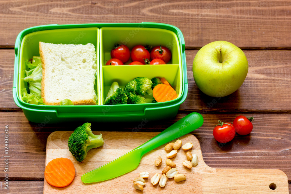 lunch box for kid with fresh vegetables on wooden background