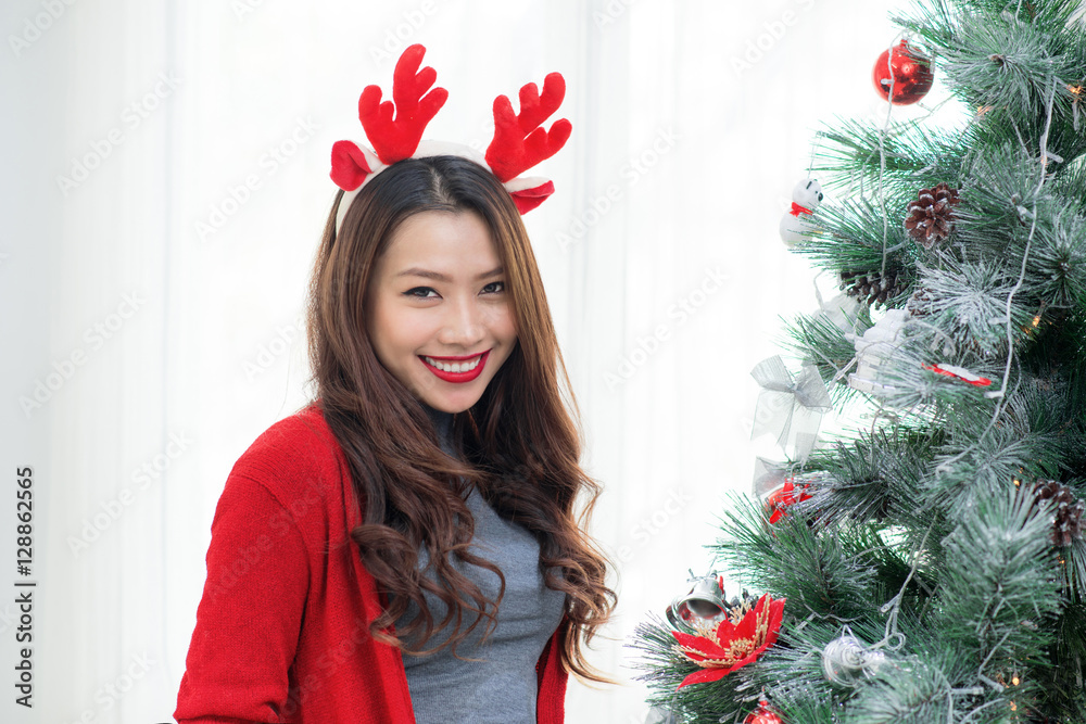 Happy young asian woman  standing near christmas tree at home ce