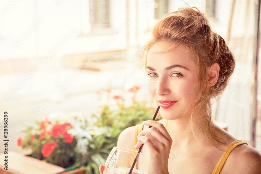 Fashion Girl Drinking Cocktail in a Cafe Terrace Outdoors. Smiling Trendy Woman in the City. Stylish