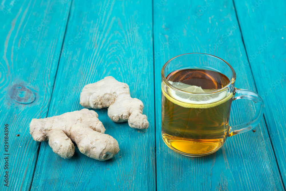 Ginger tea in a glass cup on wooden background