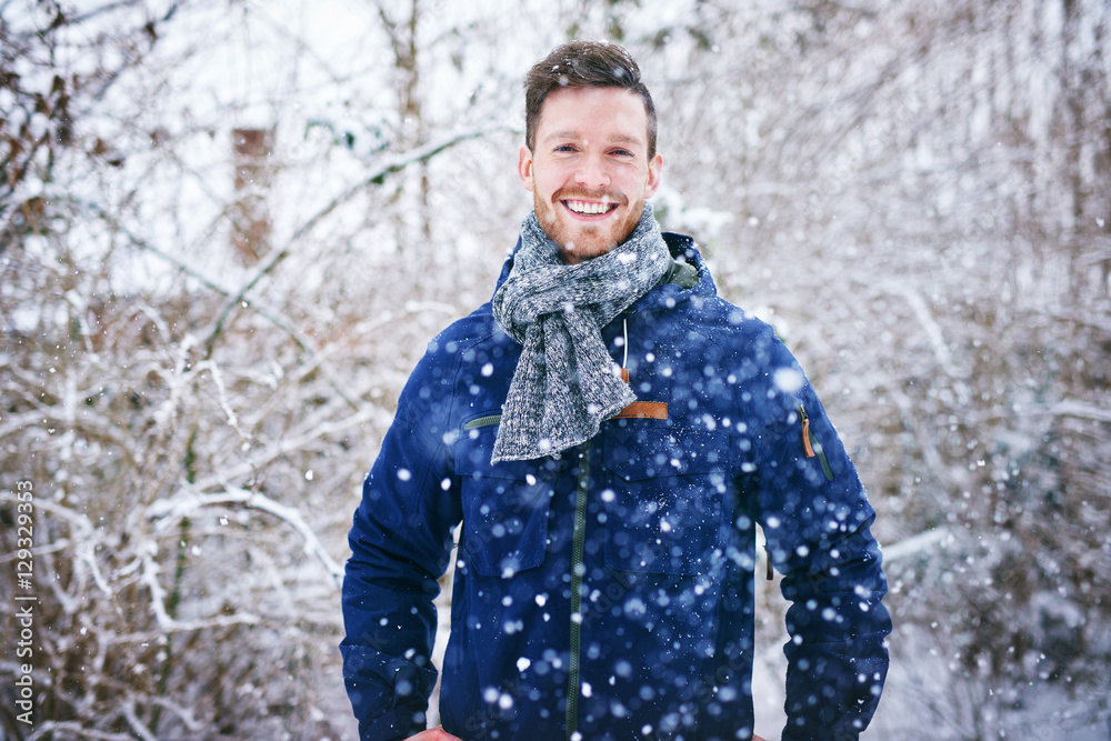 年轻英俊的男子在雪地里开心地微笑