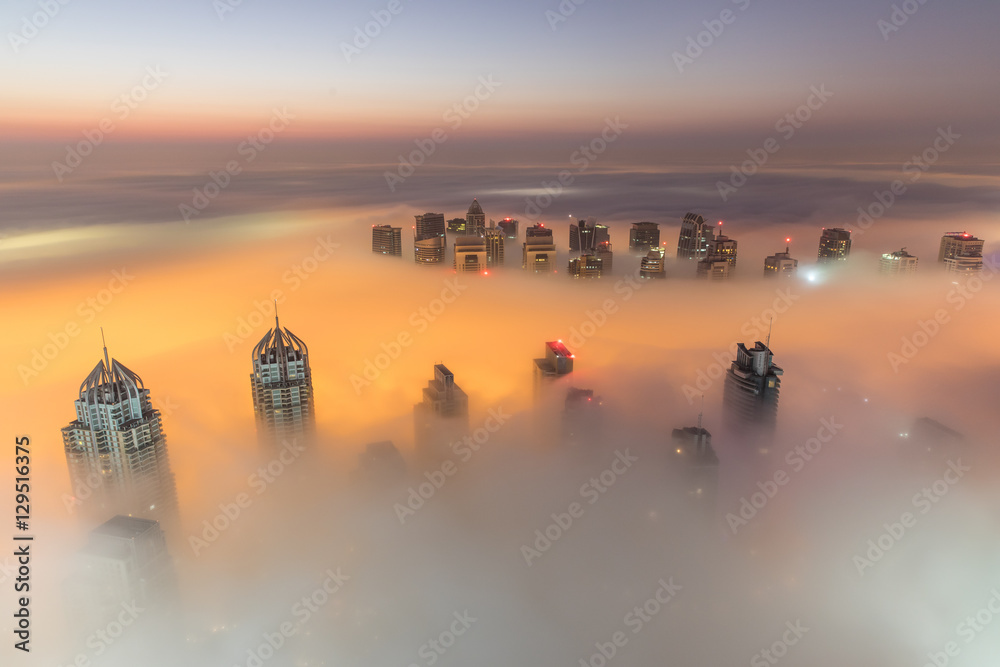 Rare early morning winter fog above the Dubai Marina skyline and skyscrapers ahead of sunrise in Dub