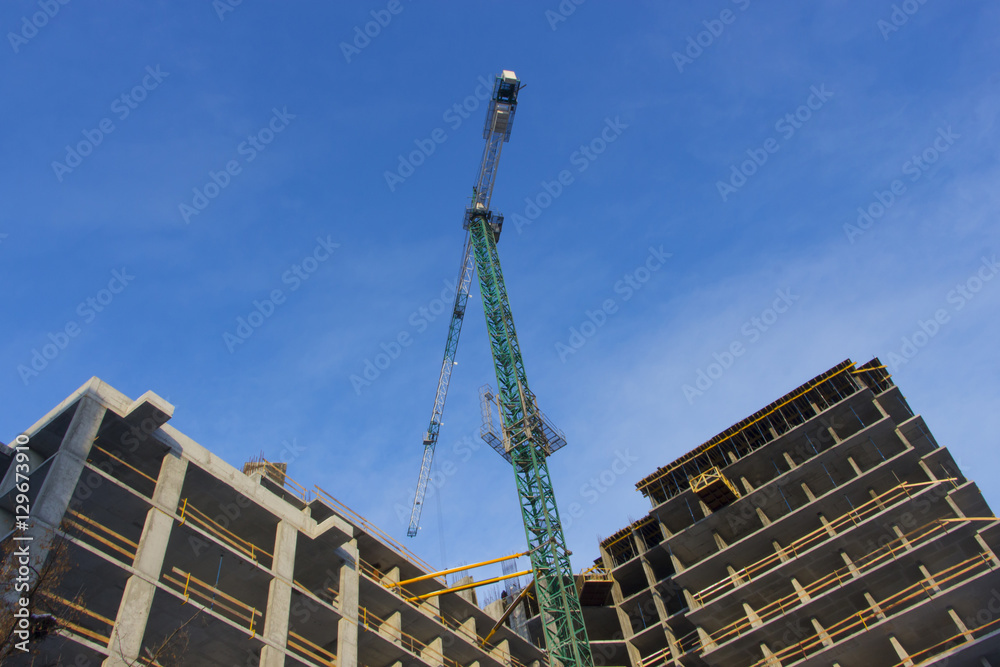 Crane and building construction site against blue sky