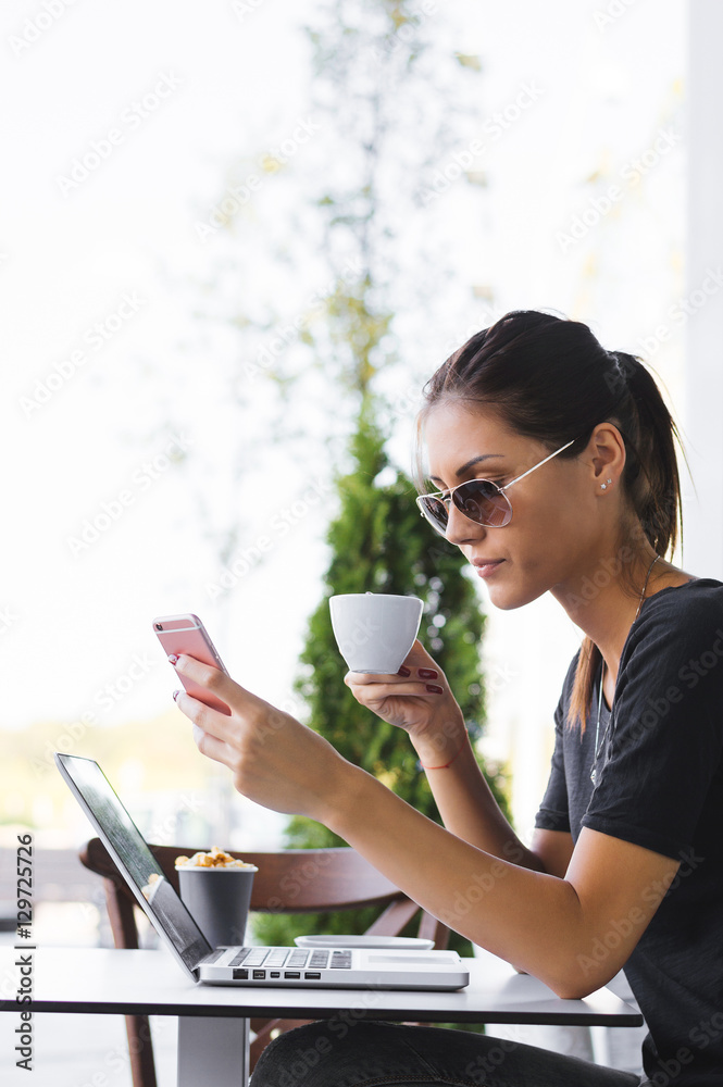 A young attractive caucasian woman uses a laptop outdoors