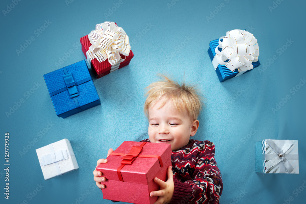 Smiling baby on red blanket with presents