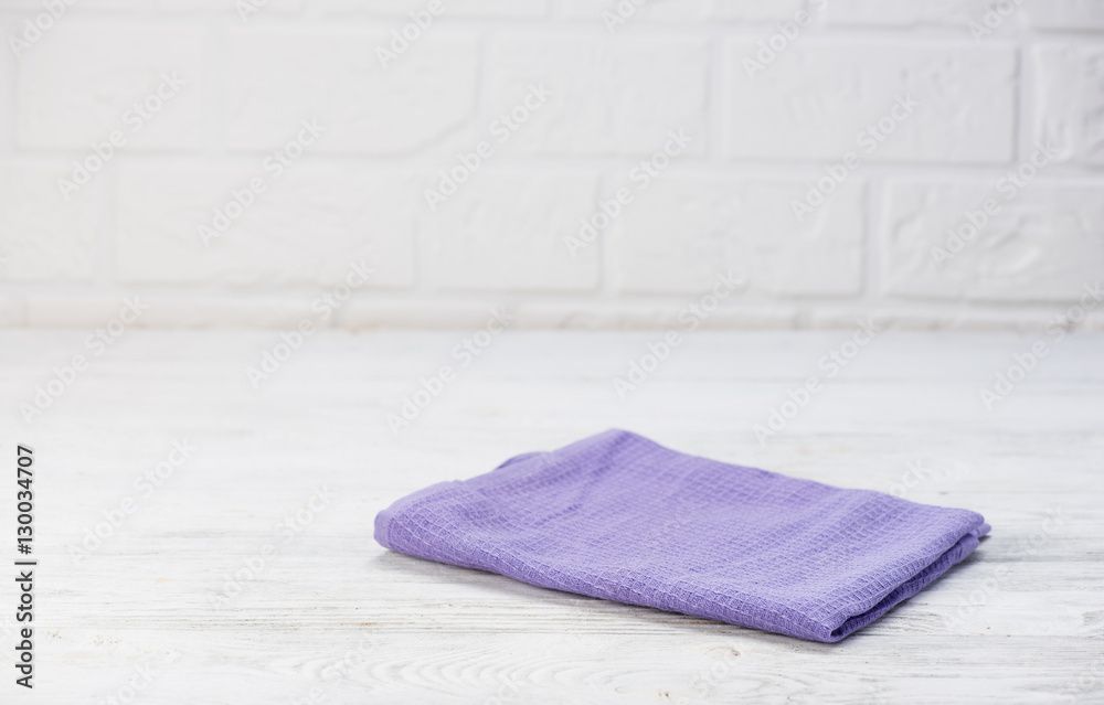 Lilac napkin isolated on white wooden table. Brick wall background. Copy space. Top view.