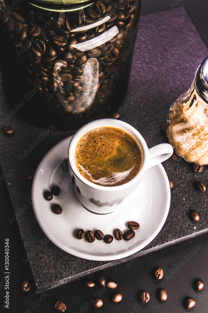 Coffee. Concept. Glass jar with beans and brown sugar cane on a dark background. Retro. Vintage. Top