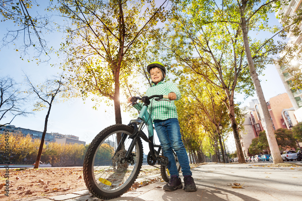 Happy boy in helmet holding bike