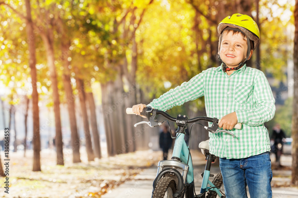 Close-up portrait of boy with bike at autumn park